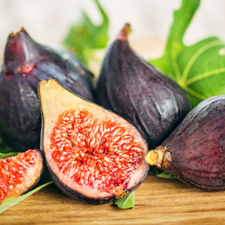 Fresh figs on a rustic wooden table with green leaves, from Little Miss Figgy Tree.